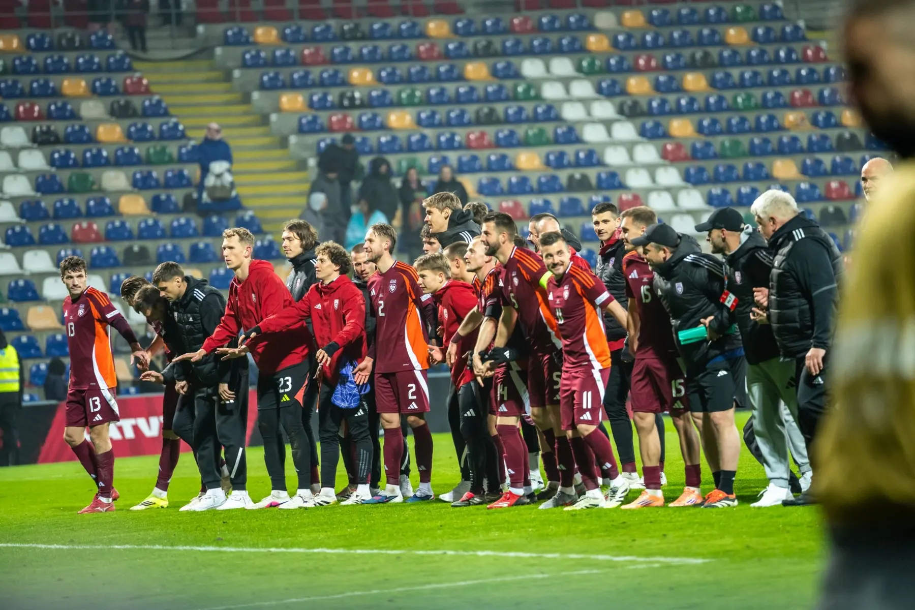 Latvian national team players and staff thanking supporters together after a match